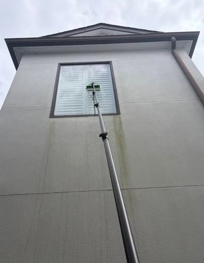 Water-fed pole cleaning a tall second-story window